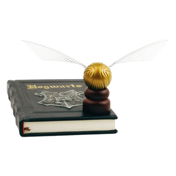 Golden Snitch replica from Harry Potter, displayed on a Hogwarts-themed book with a wooden stand against a white background